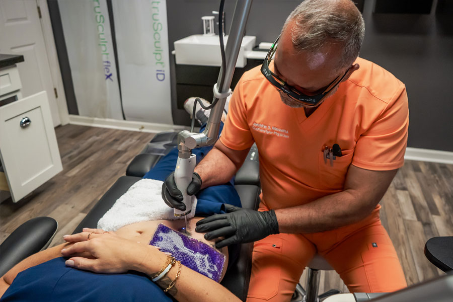 Licensed provider performing a laser tattoo removal treatment on a patient's forearm using advanced laser technology in a modern medical spa.